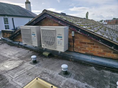 Modern HVAC system on building roof with two Fujitsu units for heating and cooling.